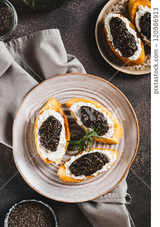 Bruschetta with cream cheese and black chia caviar on a plate top and vertical view 120986913