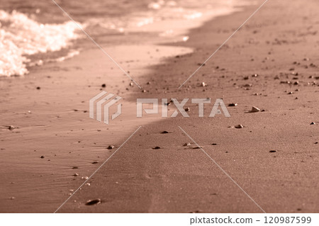 Sea wave on sandy beach with pebbles. Cozy evening abstract background. Demonstrating the colors of 2025 - Mocha Mousse. 120987599