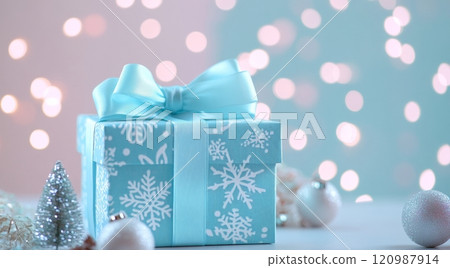 Festive blue gift box with ribbon surrounded by decorations and soft lights during the holiday season 120987914