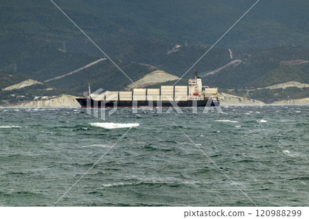 Sea freighter sailing in the middle of the ocean with big waves Sea freighter sailing in the middle of the ocean with big waves 120988299