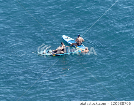 Two women in the sea sitting on SUP boards with paddles Two women in the sea sitting on SUP boards with paddles 120988706