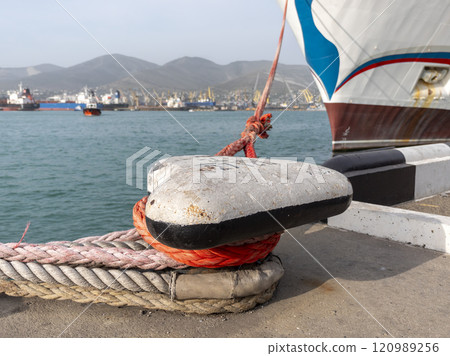 Tied rope on the knot around the mooring bollard. Nautical theme background 120989256