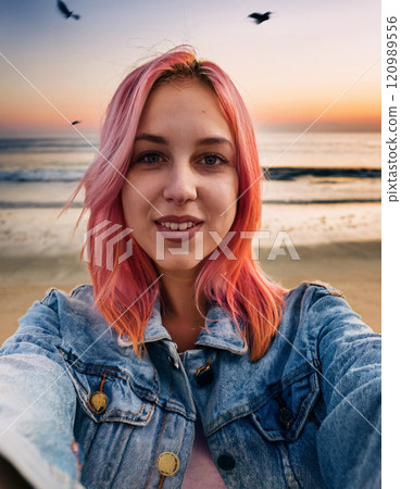 Trendy Young Woman Taking a Sunset Selfie at the Beach 120989556
