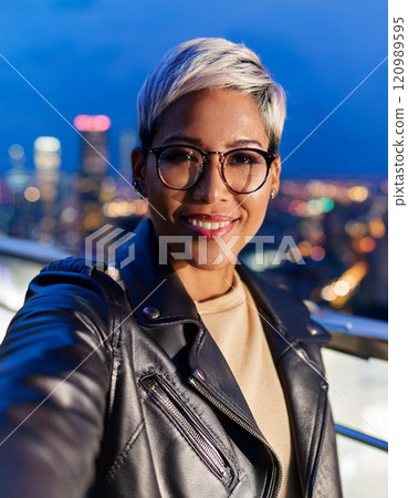 Stylish Non-Binary Person Taking a Nighttime Rooftop Selfie 120989595