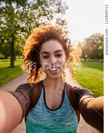 Young Woman Taking a Candid Selfie at Golden Hour in a Park 120989722