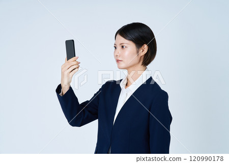 A woman in a suit operating a smartphone 120990178