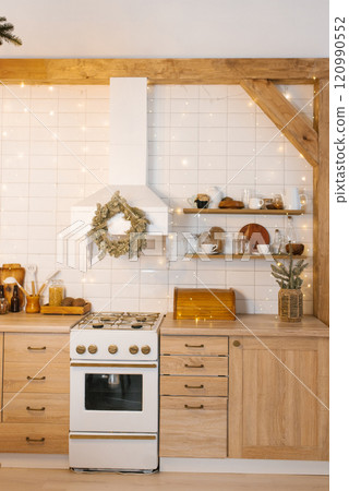 Kitchen with a white stone and christmas wreath on the hood. Cozy atmosphere Kitchen with a white stone and christmas wreath on the hood. Cozy atmosphere 120990552
