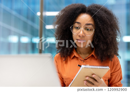 Confident woman in office, attentively writing notes on a notepad. Ideal for themes of professionalism, concentration, and business. Perfect for workplace environments and corporate presentations. Confident woman in office, attentively writing notes on a notepad. Ideal for themes of professionalism, concentration, and business. Perfect for workplace environments and corporate presentations. 120992900