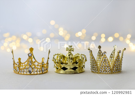 Epiphany Day or Dia de Reyes Magos concept. Three gold crowns on light sparkling background Epiphany Day or Dia de Reyes Magos concept. Three gold crowns on light sparkling background 120992981