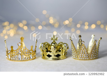 Epiphany Day or Dia de Reyes Magos concept. Three gold crowns on light sparkling background Epiphany Day or Dia de Reyes Magos concept. Three gold crowns on light sparkling background 120992982