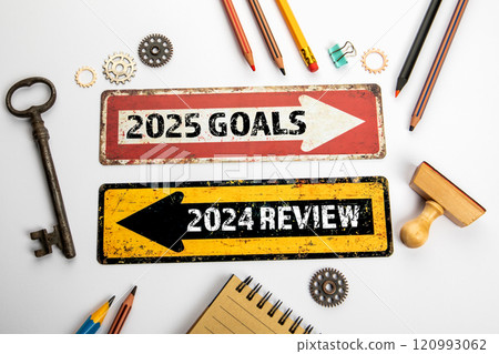 2025 Goals and 2024 Review. Two directional arrows on a white office desk 120993062