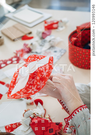 Handmaking holiday decor with red and white fabric. Showcasing festive cultural crafts and Slavic-inspired sewing traditions. Handmaking holiday decor with red and white fabric. Showcasing festive cultural crafts and Slavic-inspired sewing traditions. 120993146