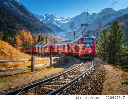 Red modern electric train traveling in alpine mountains in autumn Red modern electric train traveling in alpine mountains in autumn 120993547