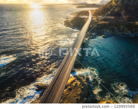 Aerial view of bridge, blue ocean and rocky coastline at sunset 120993569