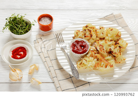 fried cauliflower florets on white plate, top view 120993762