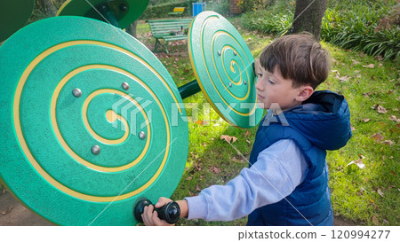 Large children's sensory toys on the playground and the child who plays with them. Concept of development of fine motor skills, Montesori for children outdoors 120994277