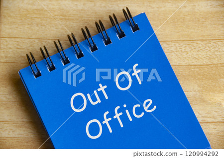 Top view of Out Of Office text on blue notepad on wooden desk. Away from work concept 120994292