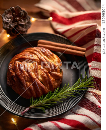 A festive Christmas pastry, shaped like a rose, served on a plate with a sprig of rosemary and cinnamon sticks A festive Christmas pastry, shaped like a rose, served on a plate with a sprig of rosemary and cinnamon sticks 120995044