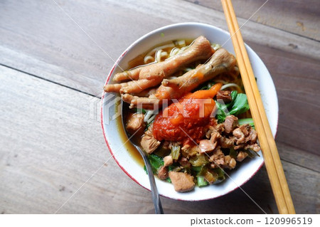 A bowl of chicken feet noodles with chili sauce. This food is street food in Indonesia. 120996519
