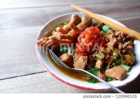 A bowl of chicken feet noodles with chili sauce. This food is street food in Indonesia. 120996520