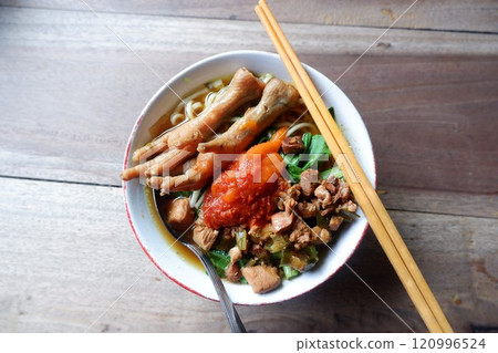 A bowl of chicken feet noodles with chili sauce. This food is street food in Indonesia. 120996524