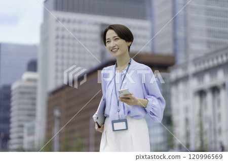 Portrait of a businesswoman with a laptop and smartphone in an office district Portrait of a businesswoman with a laptop and smartphone in an office district 120996569
