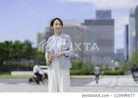 一位手持筆記本在辦公區行走的女商人的肖像 120996677