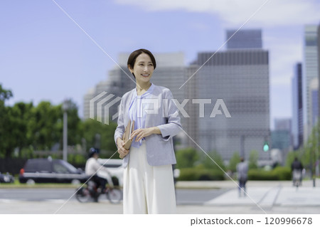 一位手持筆記本在辦公區行走的女商人的肖像 120996678