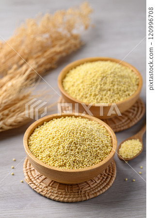 Organic yellow millet grain in wooden bowl with spoon on white table, Healthy food ingredient 120996708