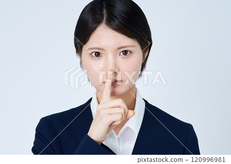 A young woman in a suit with her hand over her mouth 120996981