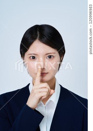A young woman in a suit with her hand over her mouth 120996983