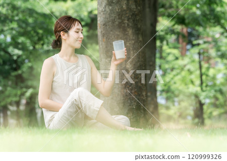 Woman drinking protein while doing yoga in the forest Woman drinking protein while doing yoga in the forest 120999326