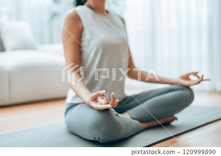 Young Asian woman meditating in lotus position at home Young Asian woman meditating in lotus position at home 120999890