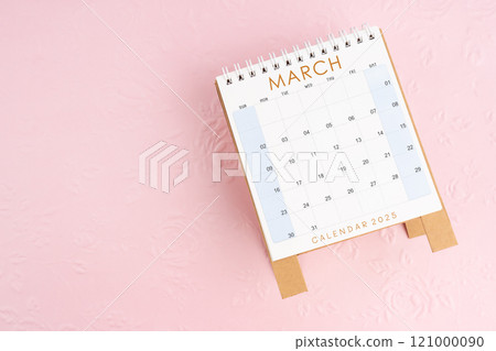 March 2025 desk calendar on pink paper with flower pattern background. 121000090