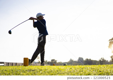Asian male amateur golfer is enjoy playing golf at golf course in morning, he is showing his beautiful swing during tee off. Man playing golf. Asian male amateur golfer is enjoy playing golf at golf course in morning, he is showing his beautiful swing during tee off. Man playing golf. 121000523