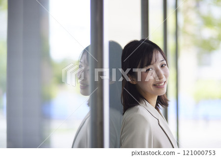 Japanese business woman in a suit leaning against a wall Japanese business woman in a suit leaning against a wall 121000753
