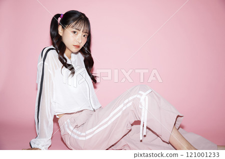 Cute portrait of a young woman in sporty clothes photographed against a pink background Cute portrait of a young woman in sporty clothes photographed against a pink background 121001233
