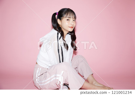 Cute portrait of a young woman in sporty clothes photographed against a pink background Cute portrait of a young woman in sporty clothes photographed against a pink background 121001234