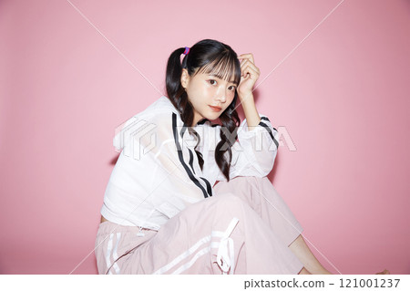 粉紅色背景下拍攝的一位穿著運動服的年輕女子的可愛肖像 121001237