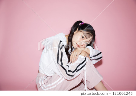 Cute portrait of a young woman in sporty clothes photographed against a pink background Cute portrait of a young woman in sporty clothes photographed against a pink background 121001245