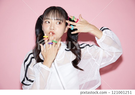 Cute portrait of a young woman in sporty clothes photographed against a pink background 121001251