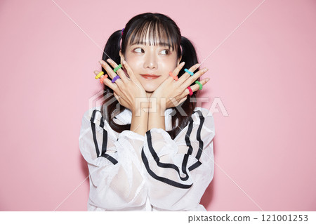 粉紅色背景下拍攝的一位穿著運動服的年輕女子的可愛肖像 121001253