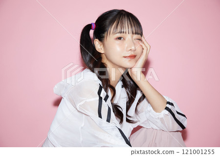 粉紅色背景下拍攝的一位穿著運動服的年輕女子的可愛肖像 121001255