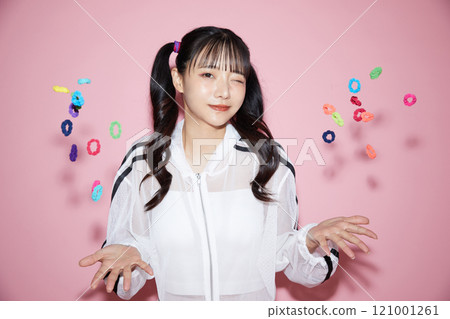 粉紅色背景下拍攝的一位穿著運動服的年輕女子的可愛肖像 121001261