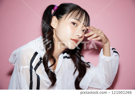 粉紅色背景下拍攝的一位穿著運動服的年輕女子的可愛肖像 121001266