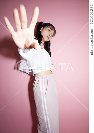 粉紅色背景下拍攝的一位穿著運動服的年輕女子的可愛肖像 121001285