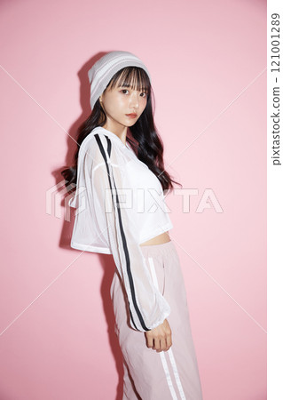 粉紅色背景下拍攝的一位穿著運動服的年輕女子的可愛肖像 121001289