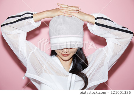 Cute portrait of a young woman in sporty clothes photographed against a pink background 121001326