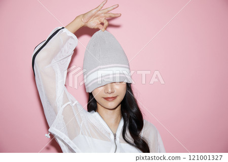 Cute portrait of a young woman in sporty clothes photographed against a pink background 121001327