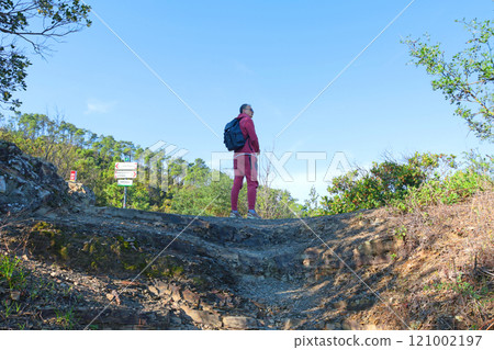 Man in sport cloth with backpack on path on top of mountain among trees. Hiking in mountains. Sport and health.  121002197